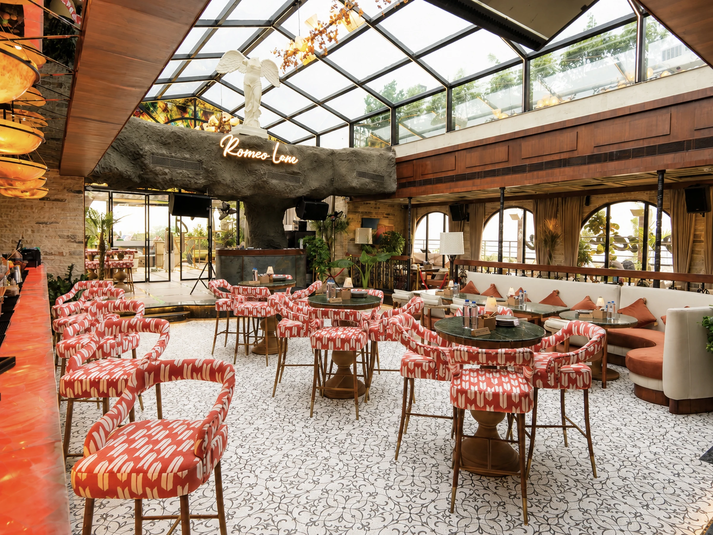 The glasshouse by day — coral ikat chairs under the glass roof
