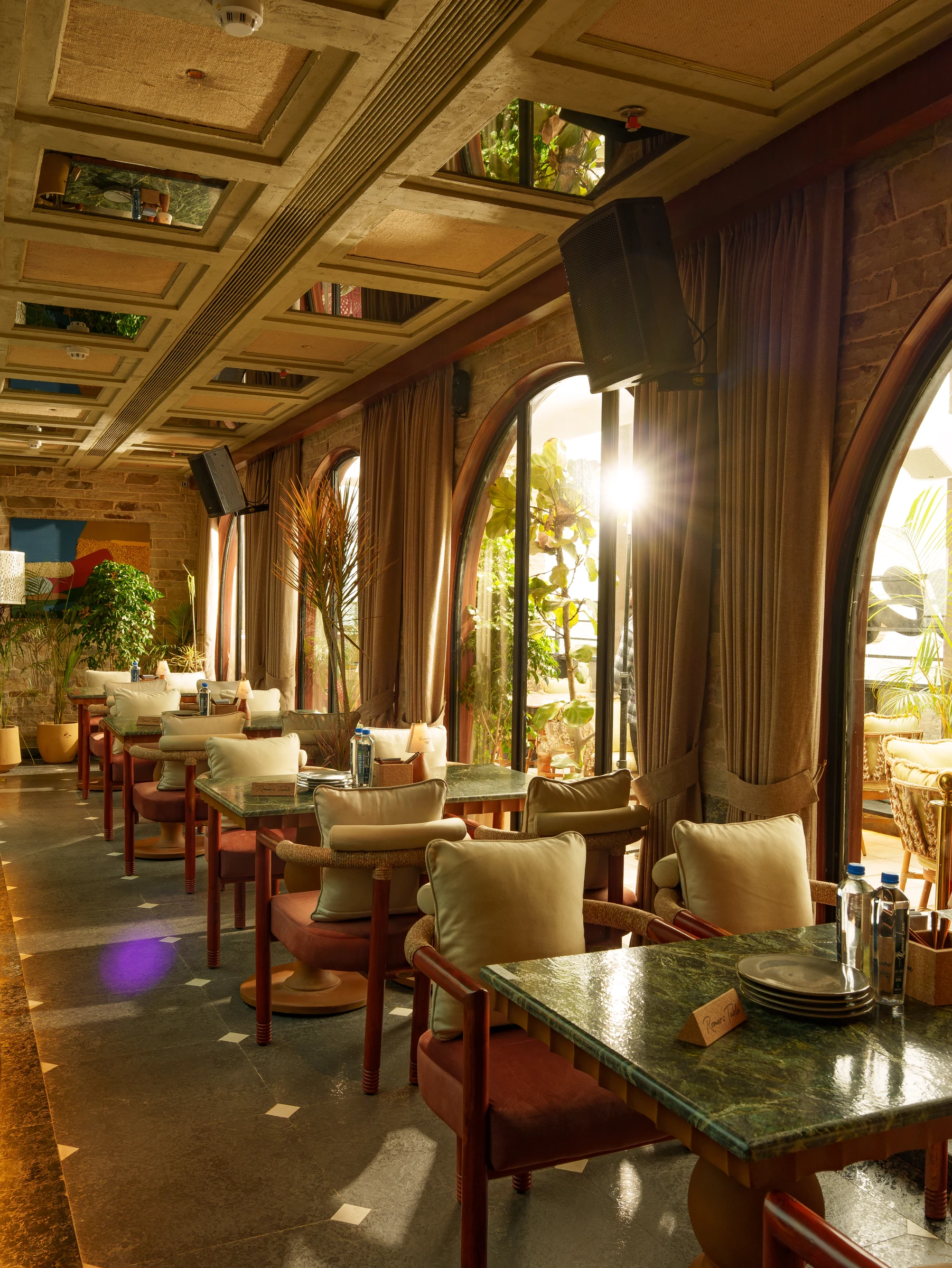 Tables by the tall arched windows, the afternoon sun coming through